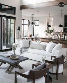 a living room filled with white furniture and lots of glass doors leading to an outside patio