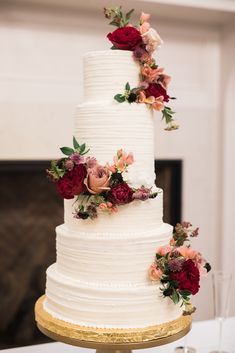 a three tiered white wedding cake with red and pink flowers