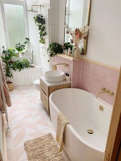 a bath room with a tub a sink and a rug on the floor in front of a window