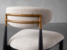 an upholstered chair with gold metal frame and fabric seat padding, viewed from the back