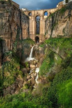 an old bridge over a small waterfall in the mountains