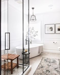 a bathroom with a bathtub, rug and pictures on the wall