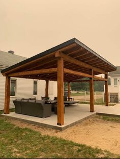 a covered patio with couches and tables in front of a white house on a cloudy day