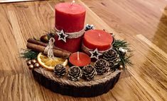 a wooden table topped with two candles and pine cones