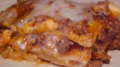 a white plate topped with lasagna covered in cheese and meat sauce on top of it