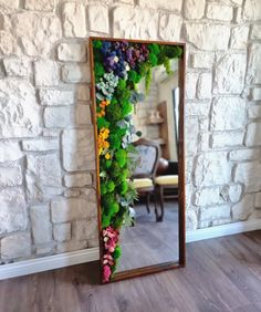 a mirror that has flowers on it in front of a brick wall and wooden floor