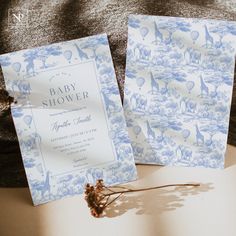 two baby shower cards sitting next to each other on top of a table with dried flowers