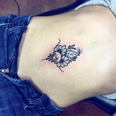 a woman's stomach with a flower tattoo on her left side ribcage