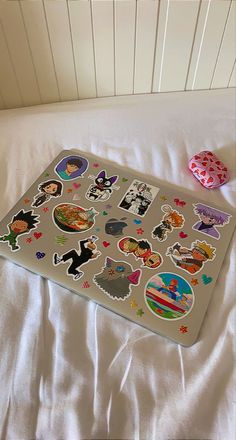 a bed topped with lots of stickers next to a white pillow covered in sheets