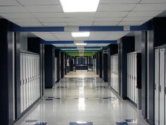 an empty hallway with blue and white tiles on the floor, leading to lockers