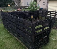 a large wooden crate sitting in the grass near a house and yard with a fence around it