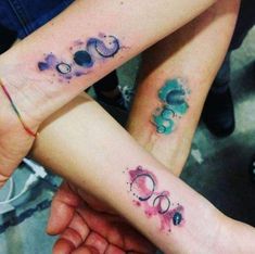 two people holding hands with tattoos on their arms and the words boo written in different colors