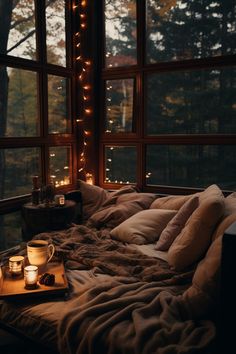 an unmade bed in front of a window with candles on it