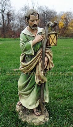 a statue of jesus holding a lantern in the grass