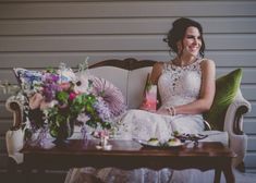 a woman sitting on top of a couch next to a table with flowers and drinks