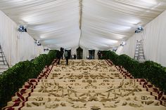 the tables are covered with white cloths and red ribboned runneres, as well as two men in black suits stand behind them