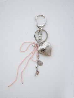 a heart shaped keychain hanging on a white wall with a pink string attached to it