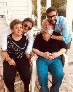 an older man and two younger women sitting on a porch with their arms around each other