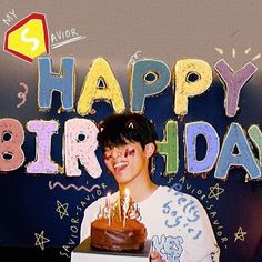 a young man holding a birthday cake with lit candles in front of the words happy birthday