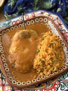 a plate with rice and meat covered in gravy on the table next to other food items