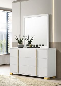 a white dresser sitting next to a window with potted plants on top of it