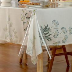 the table is covered with white linens and flowers