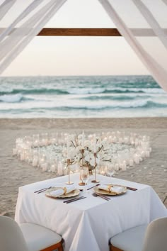 a table set up for an outdoor dinner on the beach