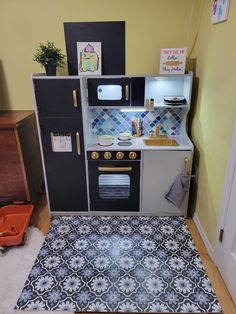 a toy kitchen with blue and white tiles on the floor