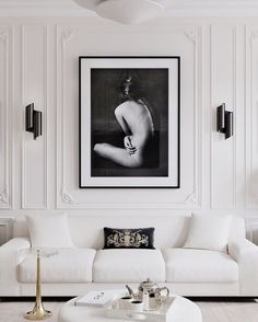 a living room filled with white furniture and art