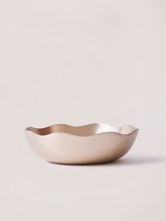 a white bowl sitting on top of a table next to a light colored wall and floor