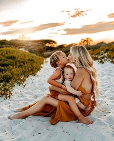 two women and a baby are sitting on the sand