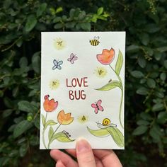 a hand holding up a card that says love bug with flowers and bees on it