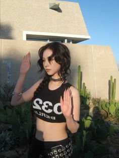 a woman standing in front of a building with her hand up to her chest and wearing a bra