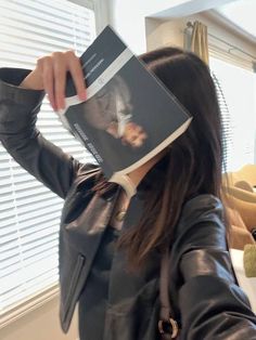 a woman holding up a book to her face