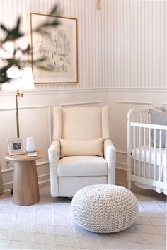 a baby's room with a white chair, crib and small round ottoman