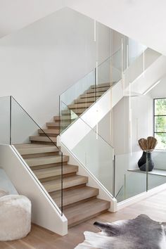 a modern staircase with glass railings and wooden steps leading up to the second floor