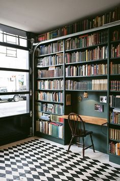 a chair sitting in front of a bookshelf filled with lots of books next to a window