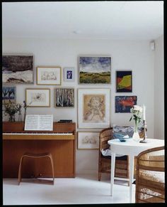 a living room filled with lots of pictures and furniture next to a piano in front of a window