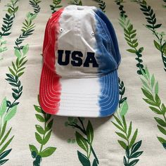 a baseball cap with the word usa painted on it sitting on a floral print tablecloth