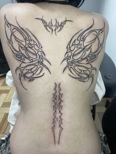 the back of a woman with tattoos on her body and wings in black ink,