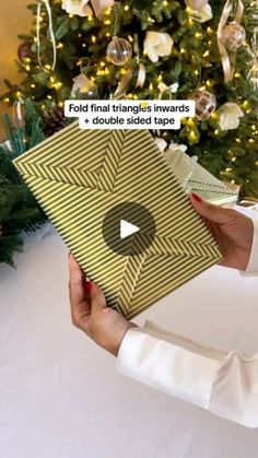 a woman holding up a christmas card with the words fold final triangles inwards and double sided tape