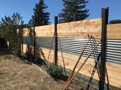 a wooden fence with metal slats in the middle and some plants growing next to it