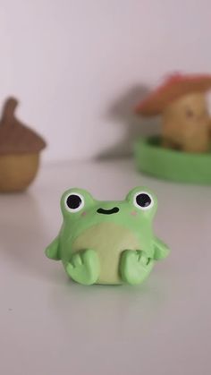 a green frog figurine sitting on top of a white table next to other toy animals