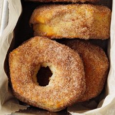 three doughnuts sitting in a paper bag