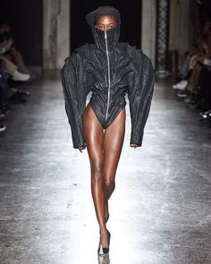 a model walks down the runway in a black outfit