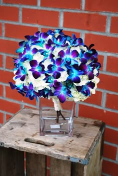 a bouquet of flowers sitting on top of a wooden table next to a brick wall