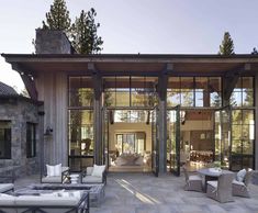 an outdoor living area with couches, tables and chairs in front of a stone building