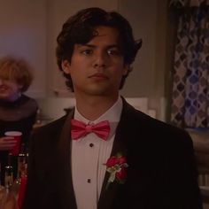 a young man in a tuxedo and red bow tie looking at the camera