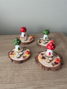 three small mushrooms are sitting on top of some wood slices with leaves and flowers painted on them