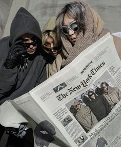 two people sitting next to each other while reading a newspaper